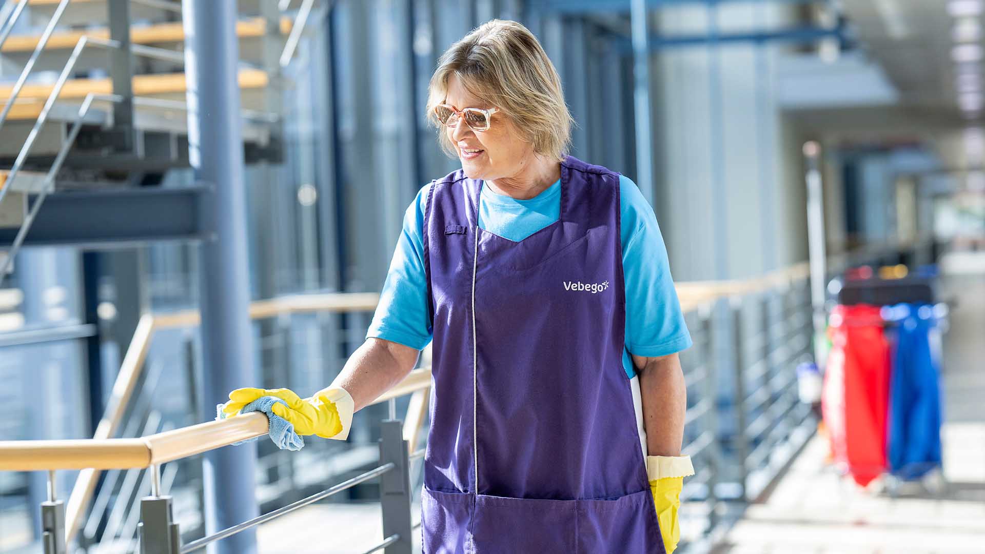 Reinigungskraft wischt Geländer