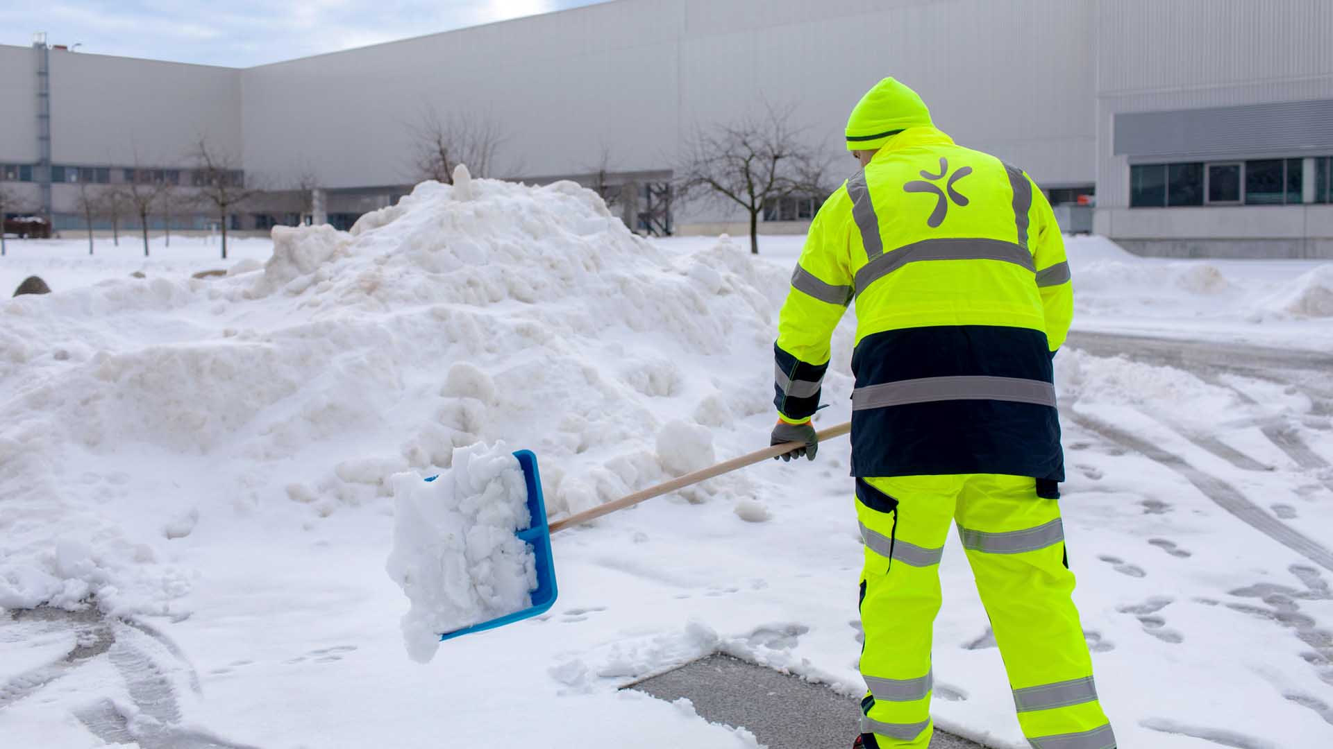 Mitarbeiter schaufelt Schnee